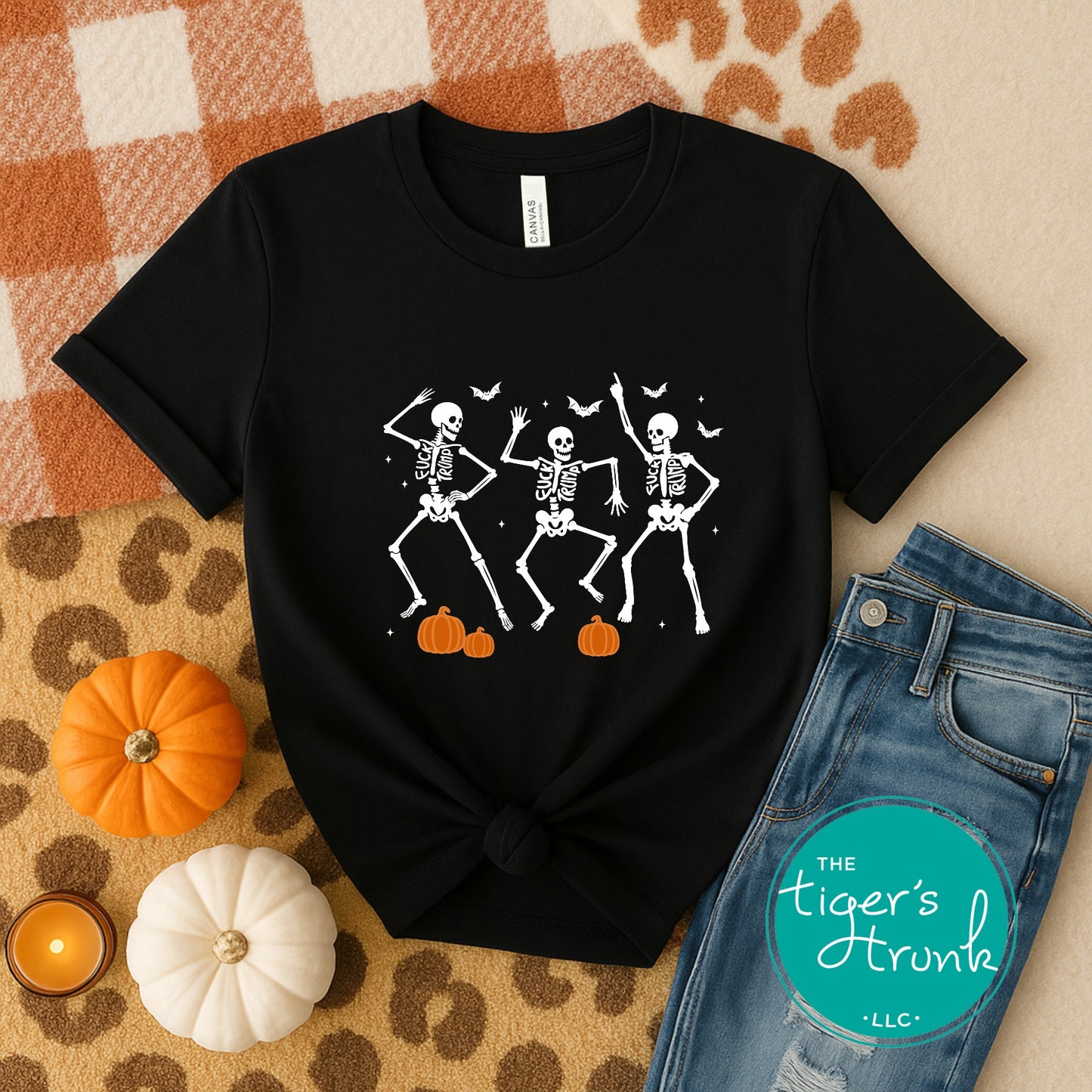 Black t-shirt with skeleton design on a checkered fabric background with pumpkins and jeans.