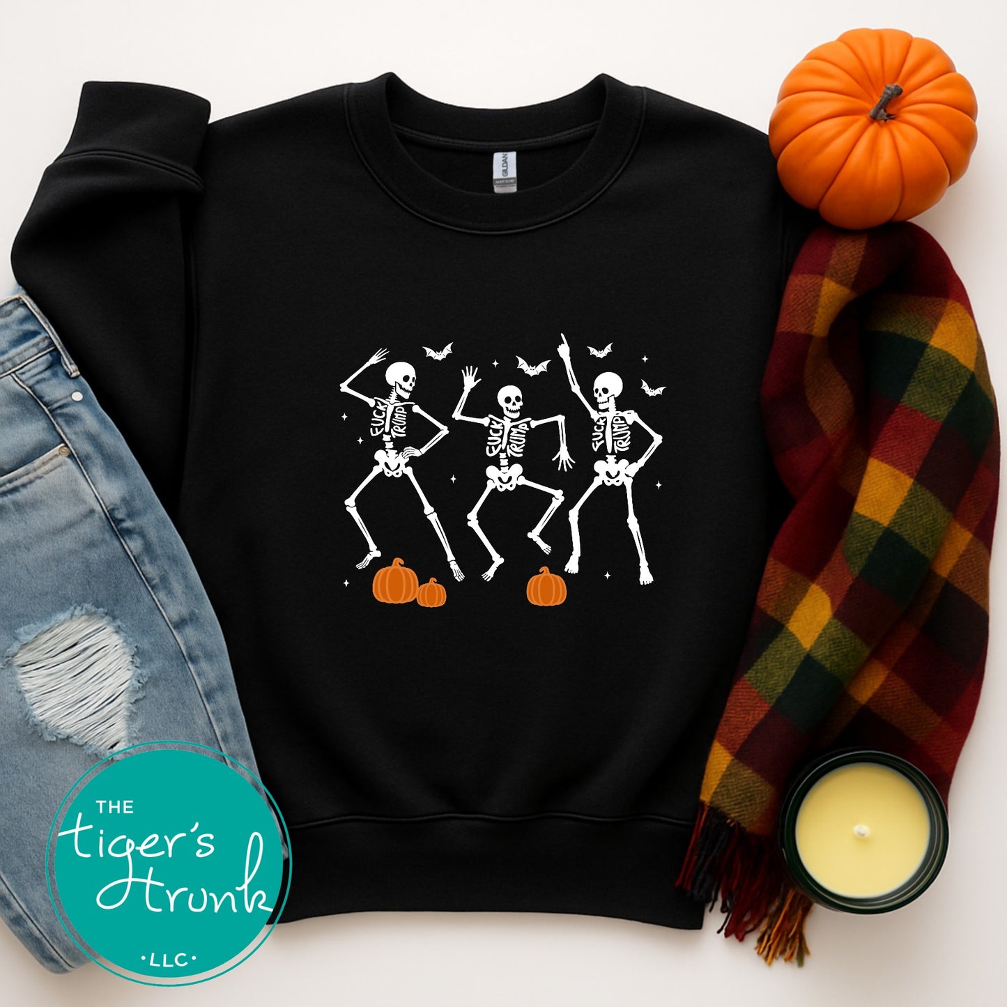 Black sweatshirt with skeleton design, orange pumpkin, plaid scarf, and candle on a white background.