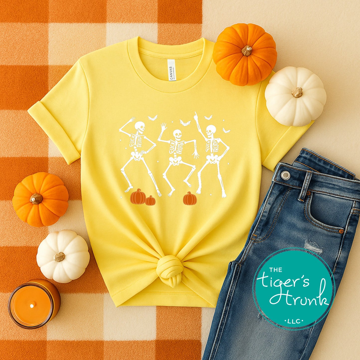 Yellow t-shirt with skeleton design, blue jeans, and pumpkins on a checkered background