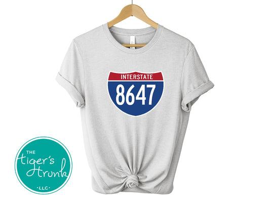 T-shirt featuring 8647 inside an Interstate sign, clean and bold design with a subtle political message