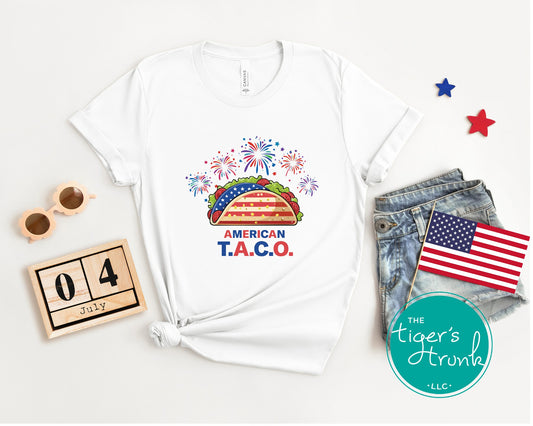 Patriotic t-shirt featuring fireworks and a taco reading American T.A.C.O., a subtle political satire tee for July 4th cookouts