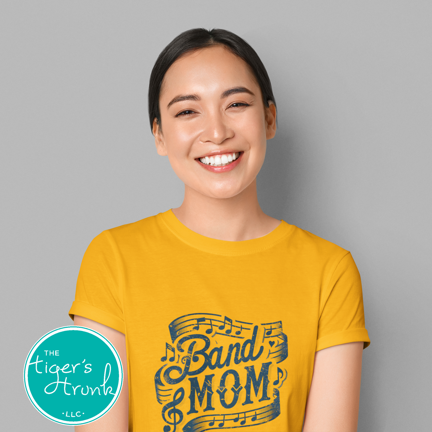Woman wearing a yellow 'Band Mom' t-shirt with a gray background