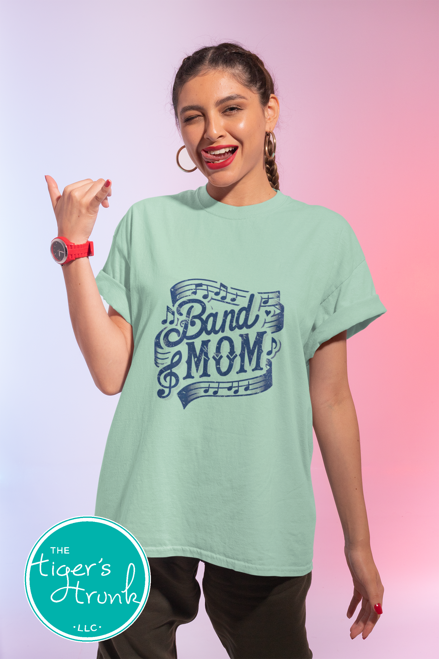 Woman wearing a light green t-shirt with 'Band Mom' text, posing against a gradient background.