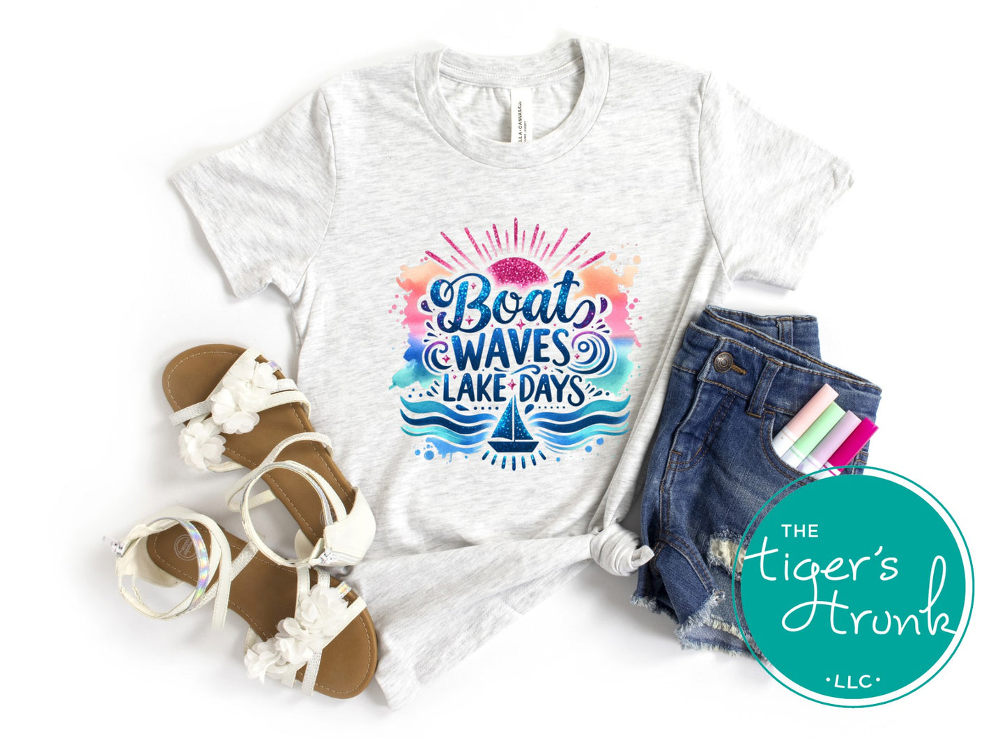 White t-shirt with 'Boat Waves Lake Days' design, sandals, shorts, and stationery on a white background.