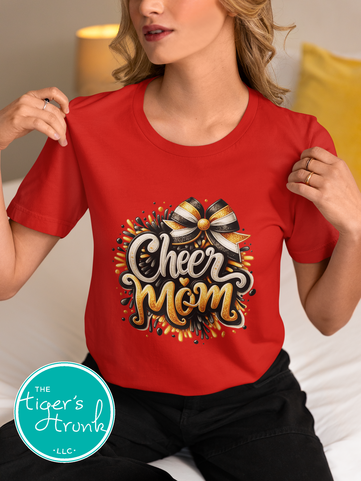 Person wearing a red 'Cheer Mom' t-shirt with decorative elements, sitting on a couch.
