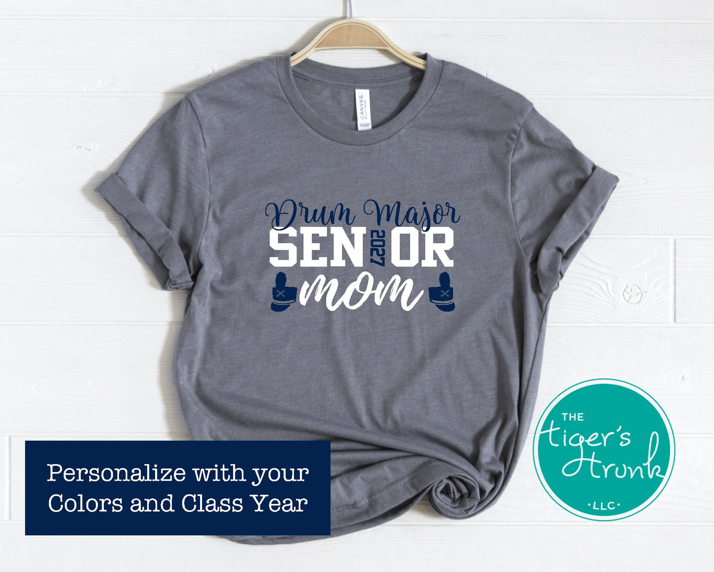 Gray t-shirt with 'Drum Major Senior Mom' text on a hanger, branded with 'The Tiger's Trunk'.