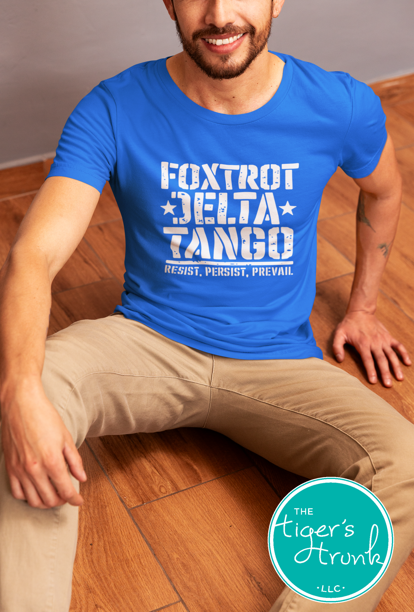 Man wearing a blue t-shirt with text, sitting on a wooden floor.