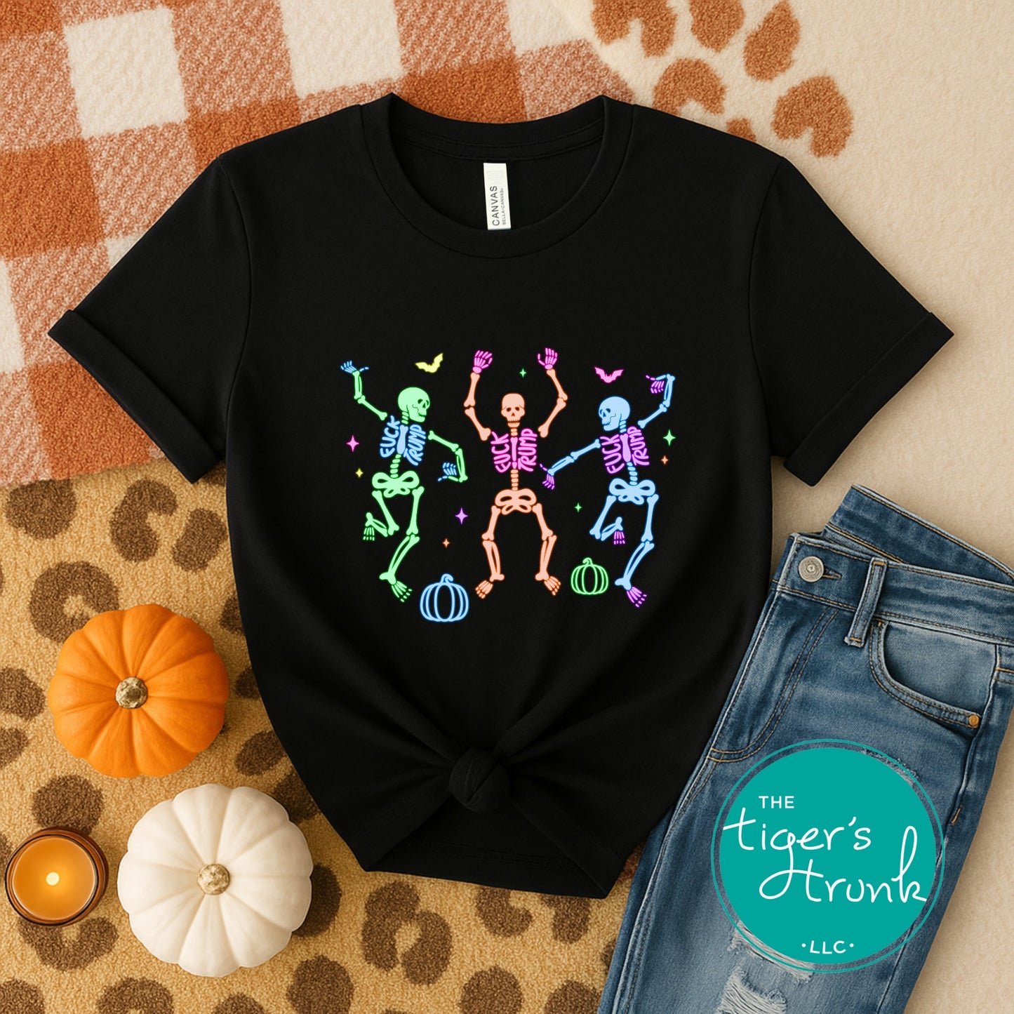 Black t-shirt with colorful skeleton design on a checkered fabric background with pumpkins and jeans.