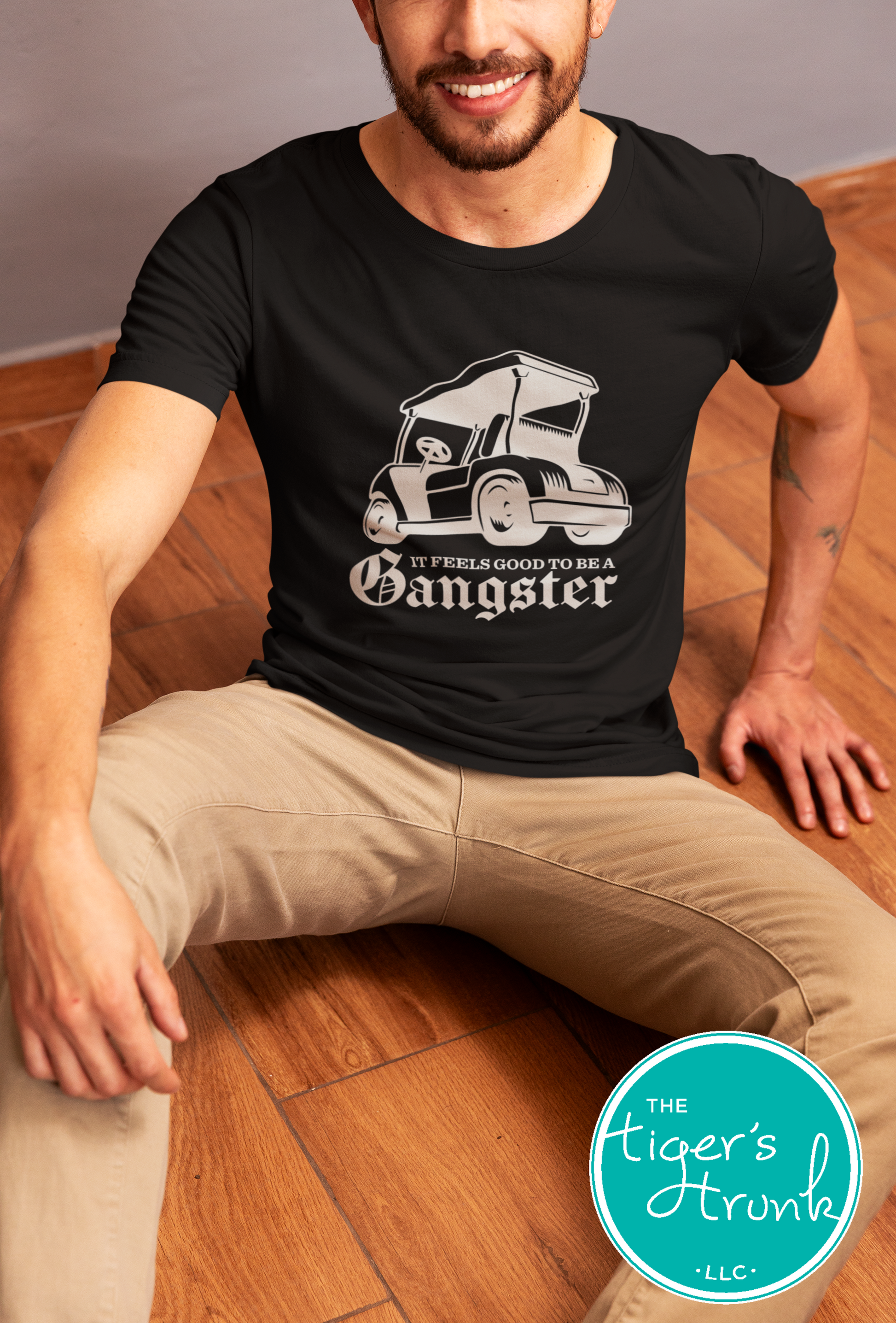 Male model wearing black golf cart shirt with light tan graphic that says It Feels Good to Be a Gangster, funny golf tee for men, golfer gift idea
