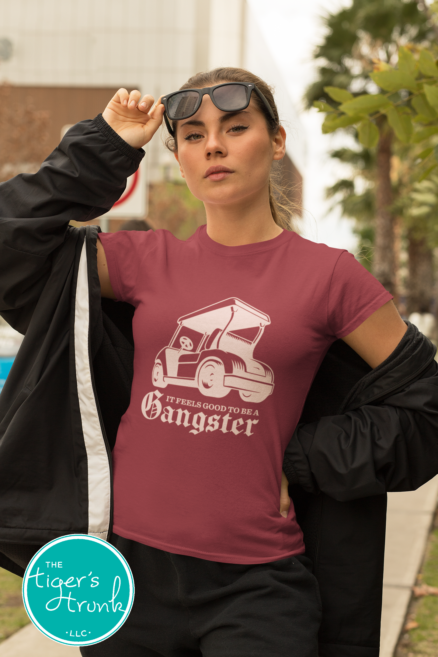 Female model wearing maroon golf cart shirt with light melon graphic that says It Feels Good to Be a Gangster, funny golf shirt for women