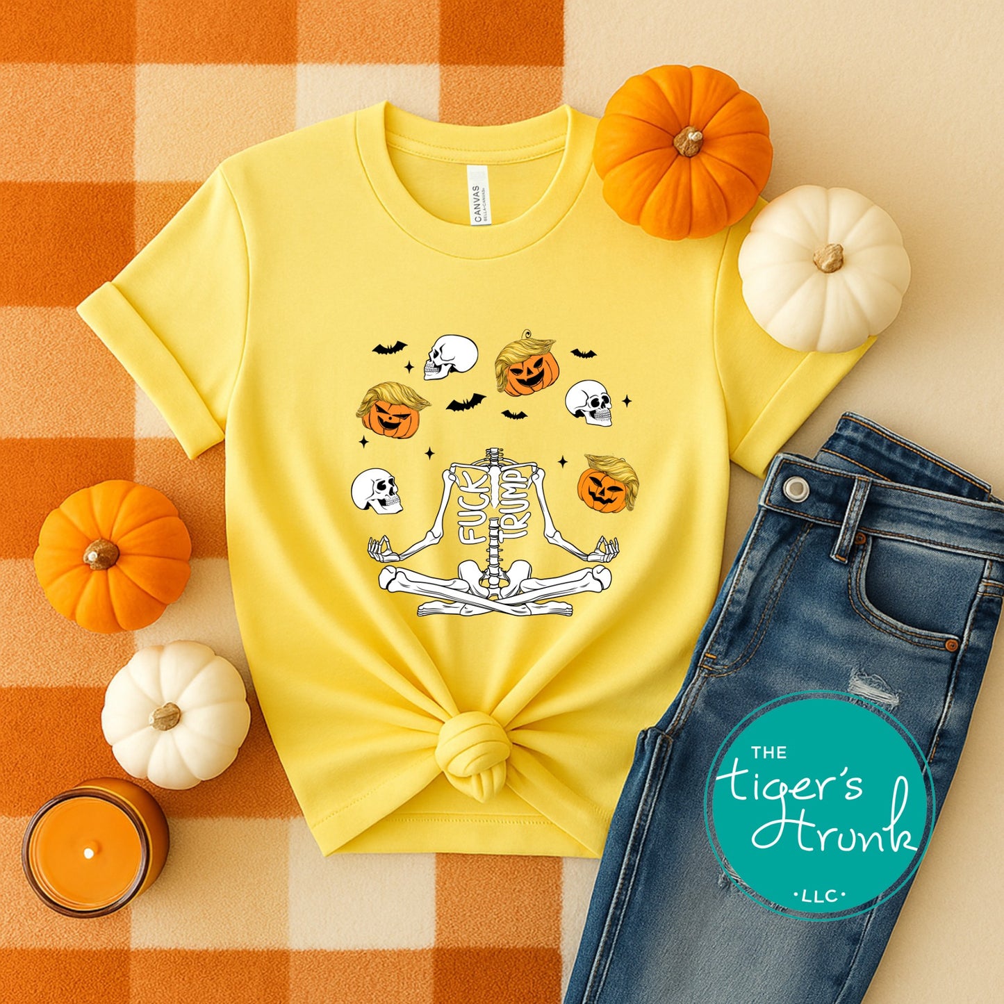 Yellow t-shirt with Halloween design, blue jeans, and pumpkins on a checkered background