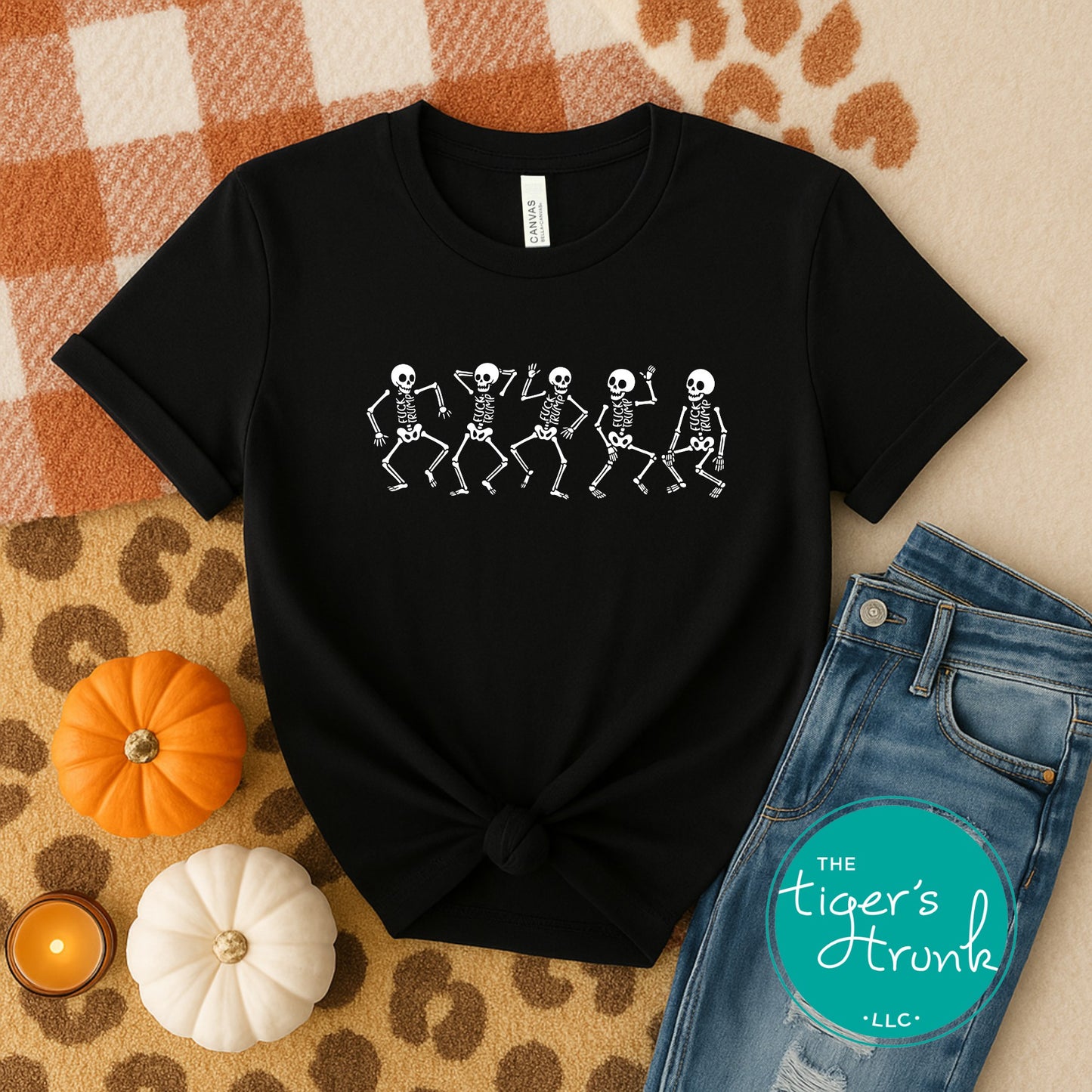 Black t-shirt with skeleton design on a checkered fabric background with pumpkins and jeans.