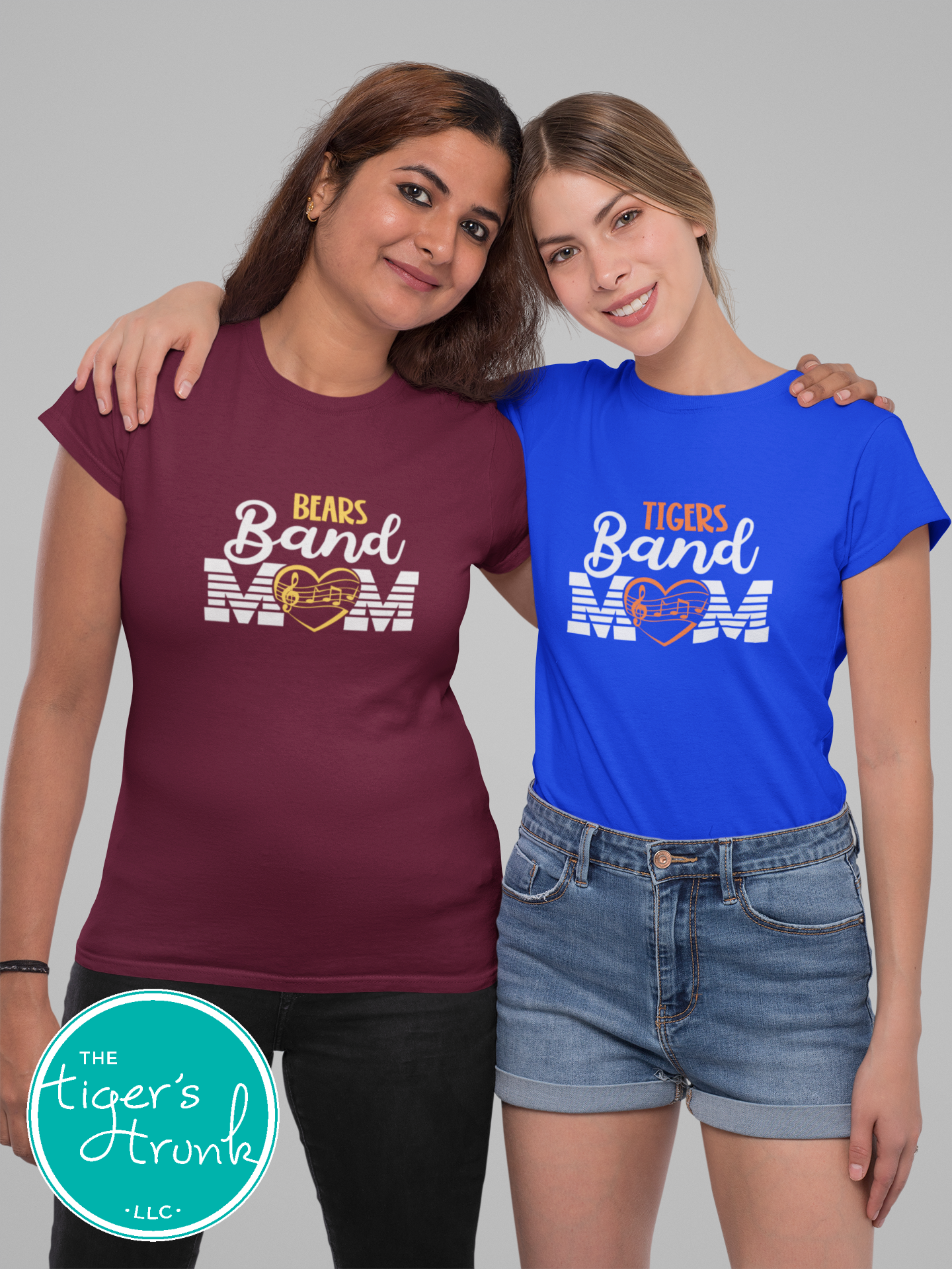 Two women wearing t-shirts with 'Bears Band Mom' and 'Tigers Band Mom' text, standing side by side against a gray background.