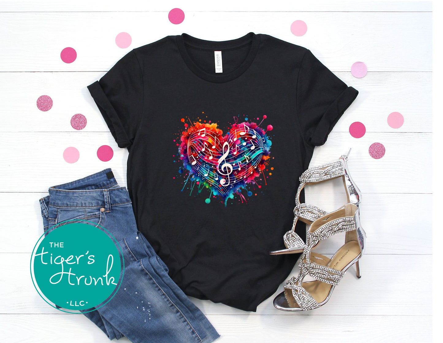 Black t-shirt with colorful heart and music note design, paired with jeans and high heels on a white background.
