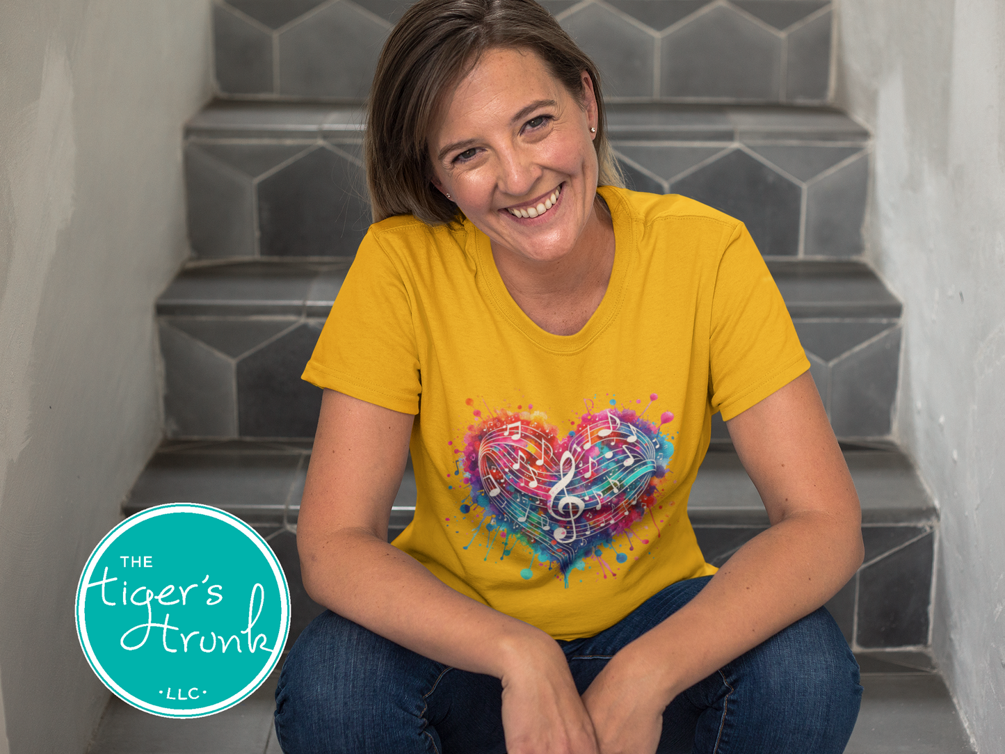 Woman wearing a yellow t-shirt with a colorful heart design, sitting on steps.