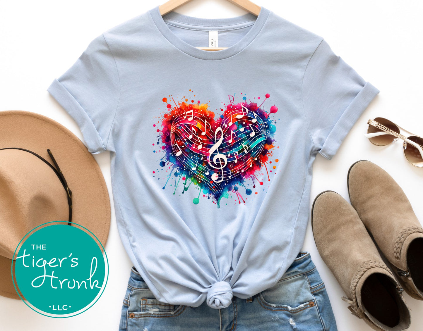 Light blue t-shirt with colorful heart design, paired with a hat, sunglasses, and boots on a white background.