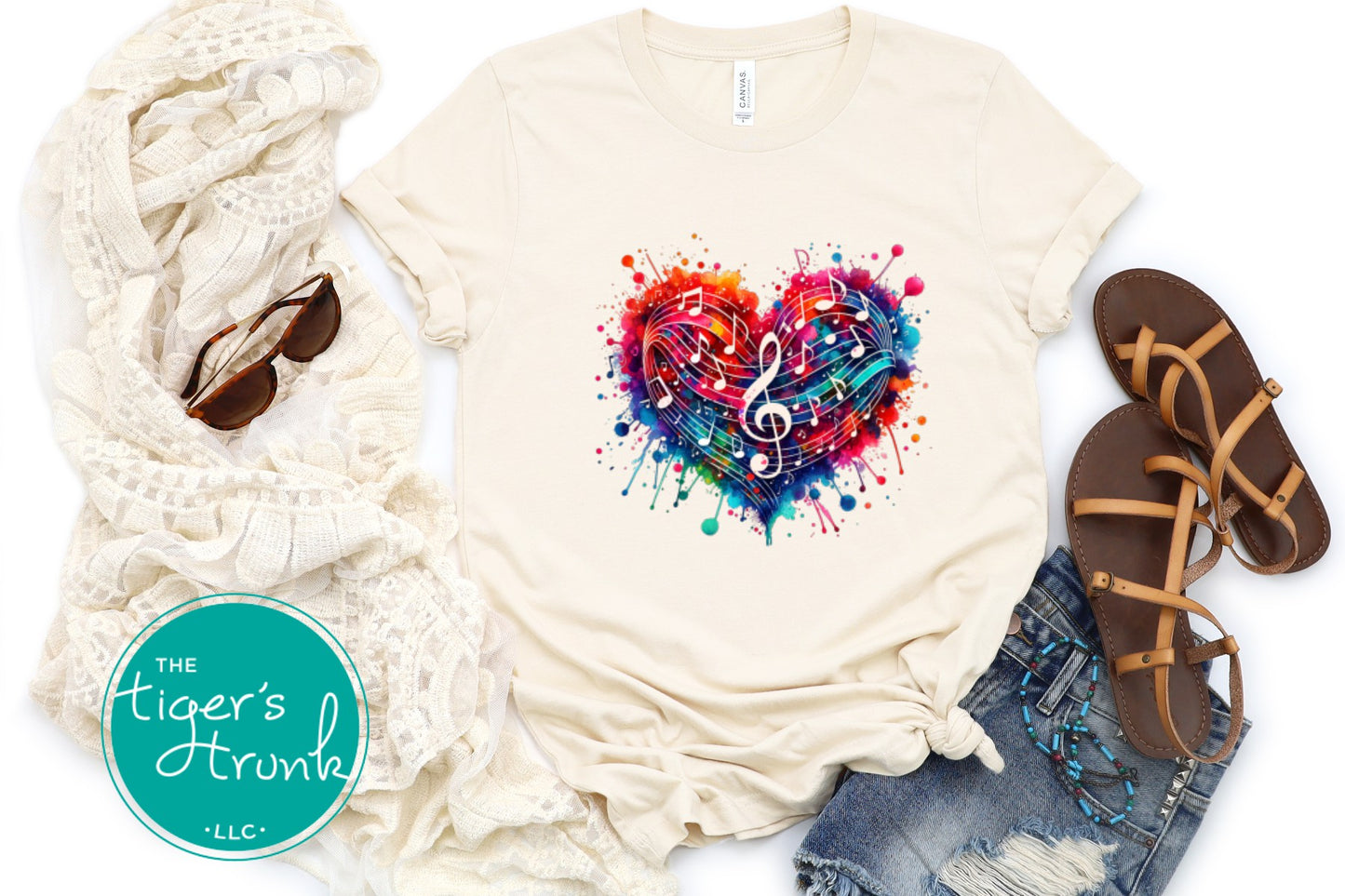 Beige t-shirt with colorful heart design, scarf, sunglasses, and sandals on a white background.