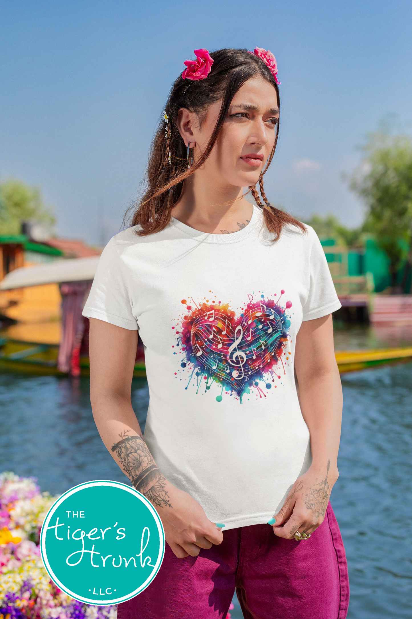 Woman wearing a white t-shirt with a colorful heart design in a scenic outdoor setting.