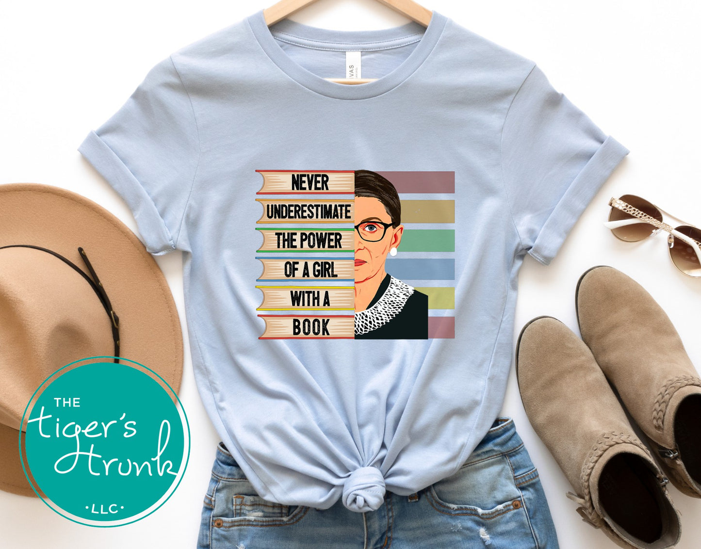 Light blue t-shirt with graphic design and text, placed on a white surface with accessories.