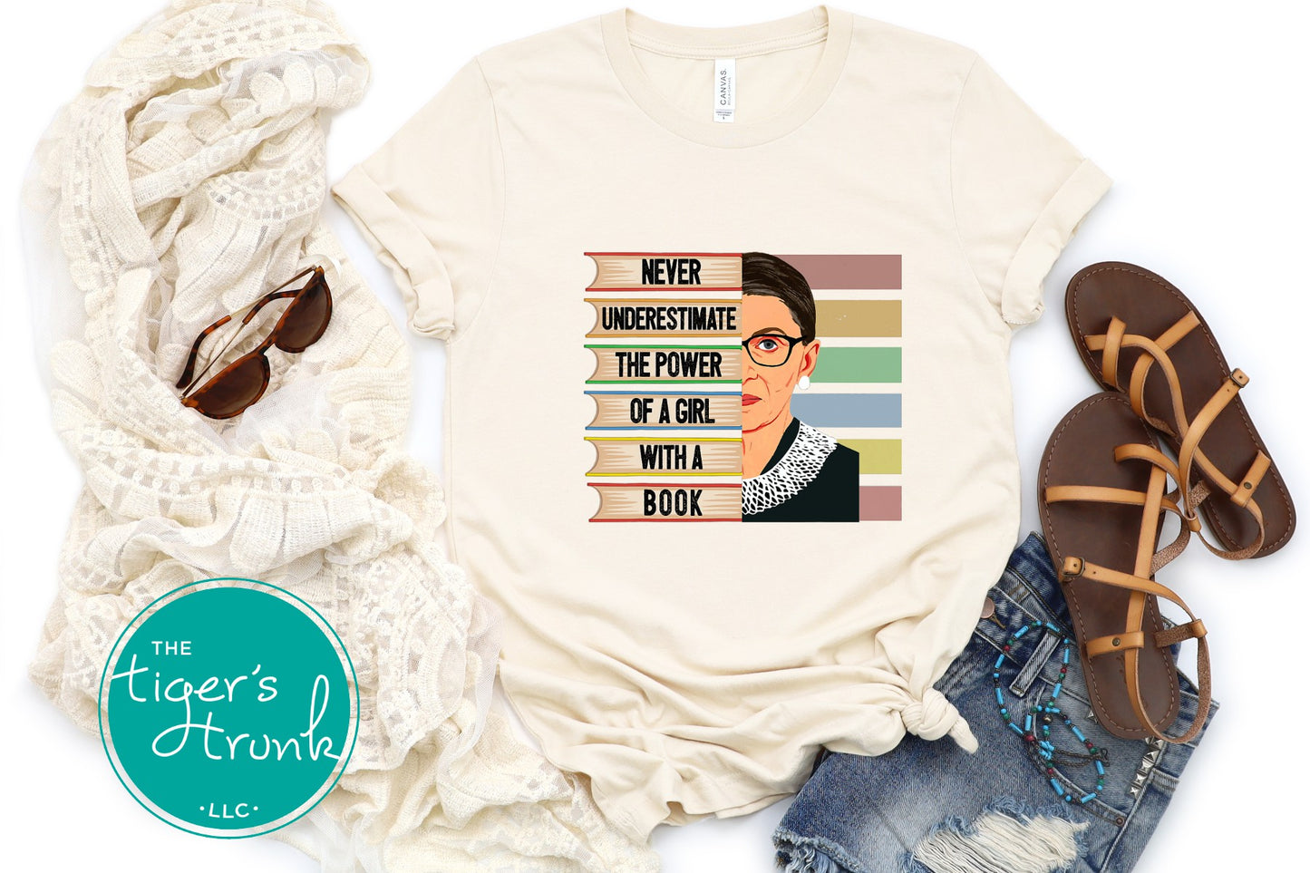 T-shirt with a graphic design of a person with glasses and text, paired with a scarf, sunglasses, and sandals on a white background.