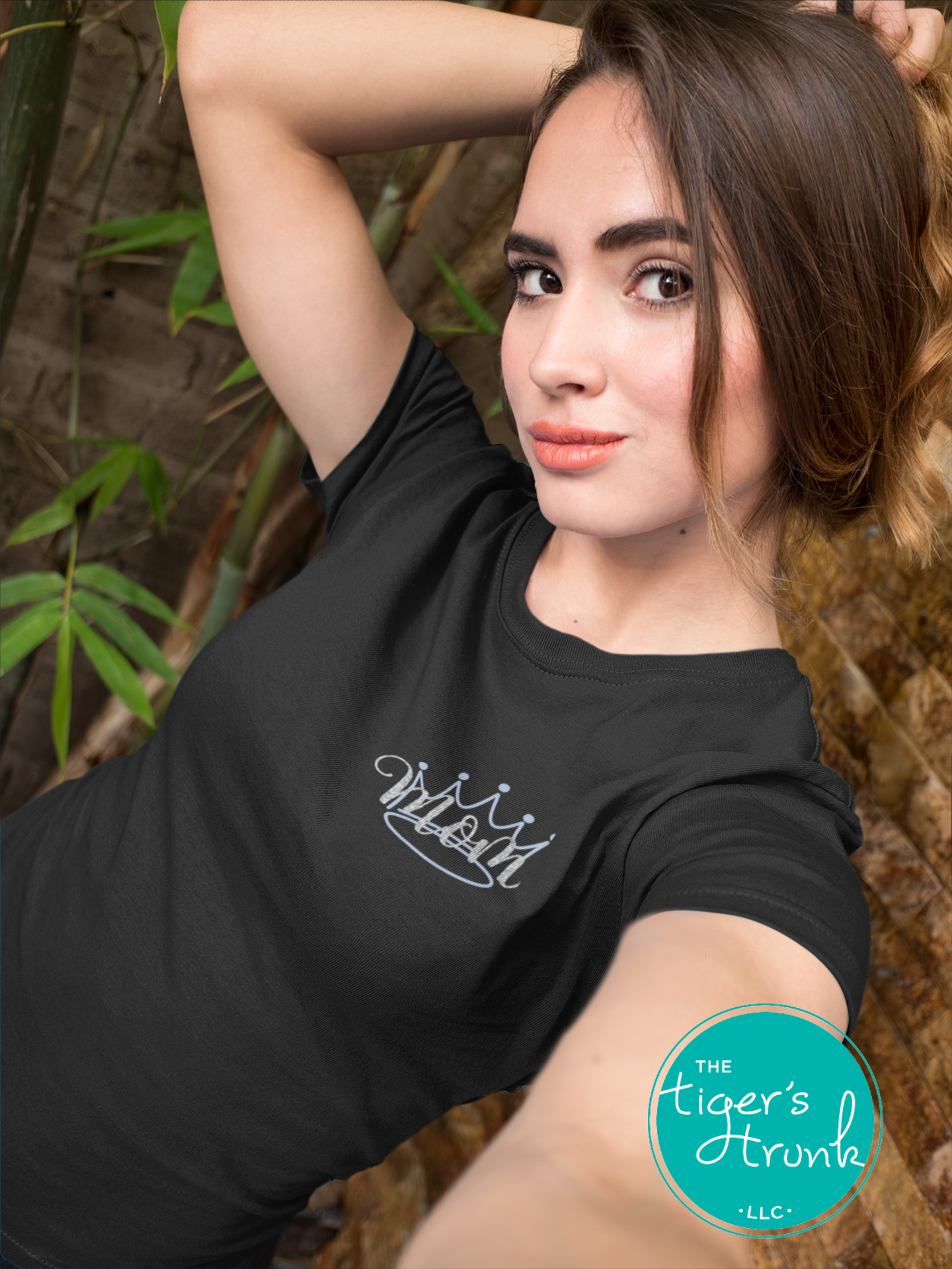 Model wearing black pageant mom shirt with blue crown and “Mom” in script font on the front, personalized on the back with contestant’s name in block letters