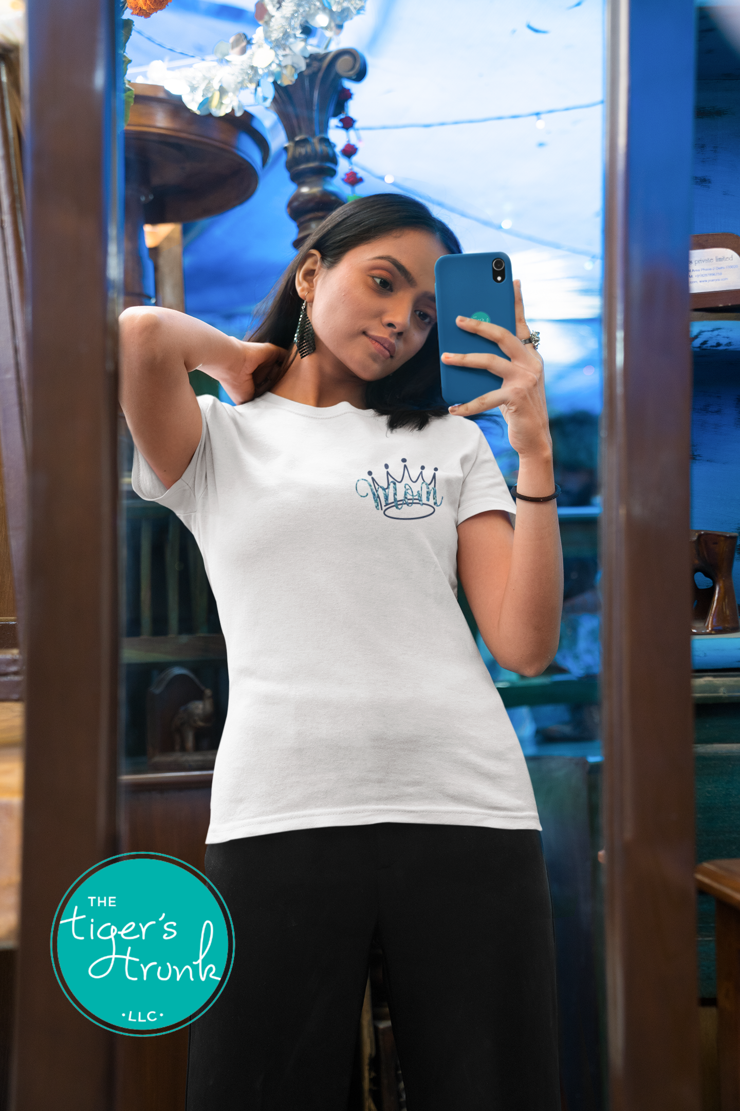 Model wearing white pageant mom shirt with blue crown and “Mom” in script font on the front, personalized on the back with contestant’s name in block letters