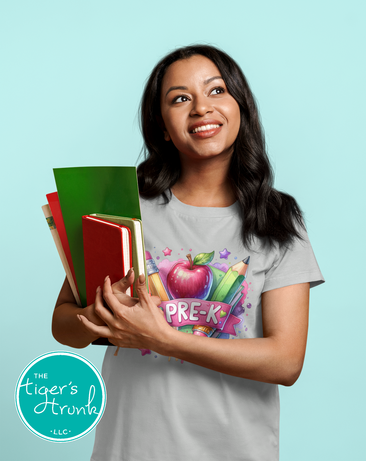 Woman holding books and wearing a 'PRE-K' t-shirt against a light blue background