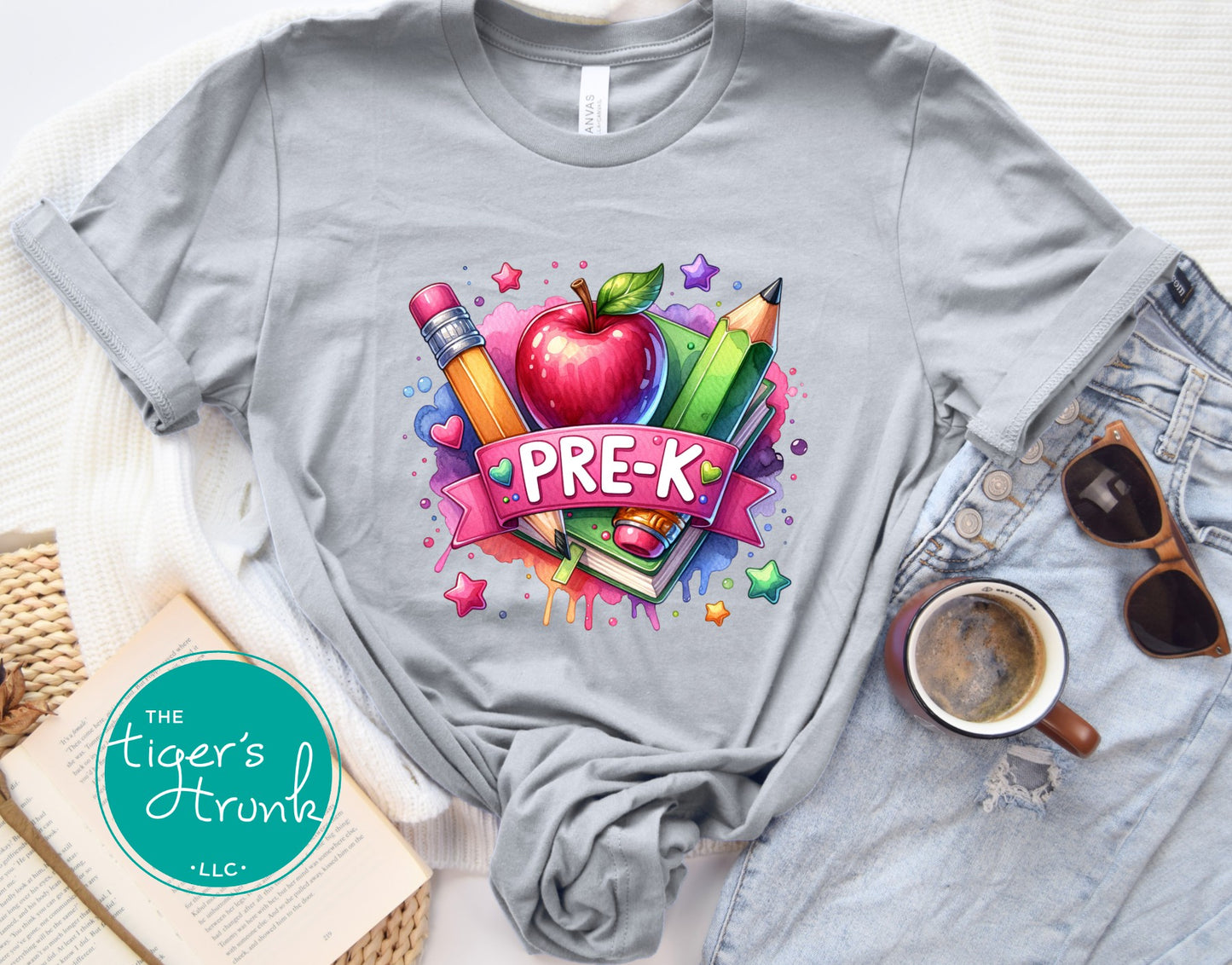 Gray t-shirt with colorful 'PRE-K' design on a white surface with accessories.
