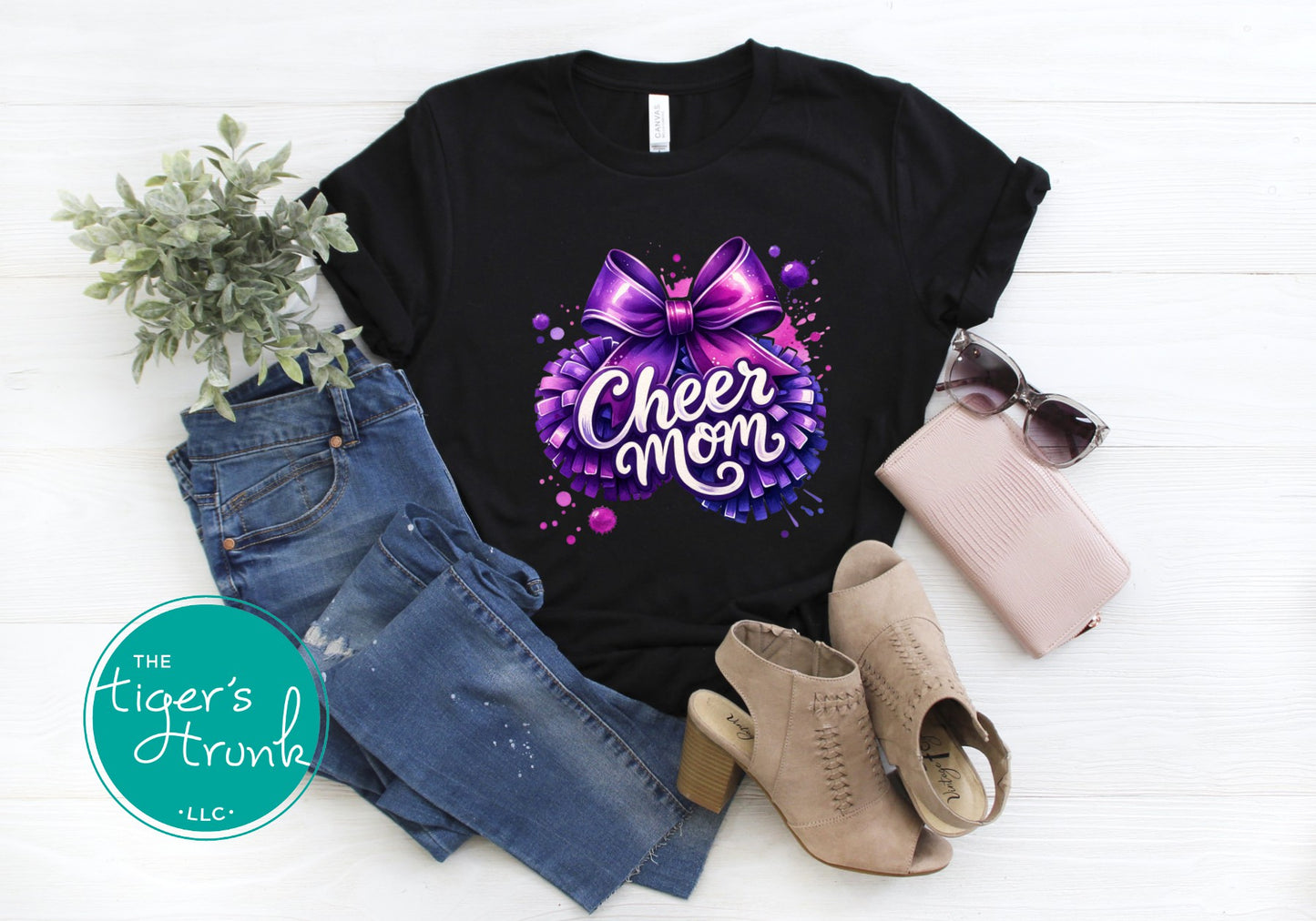 Black t-shirt with 'Cheer Mom' design, paired with jeans, boots, and sunglasses on a white background.