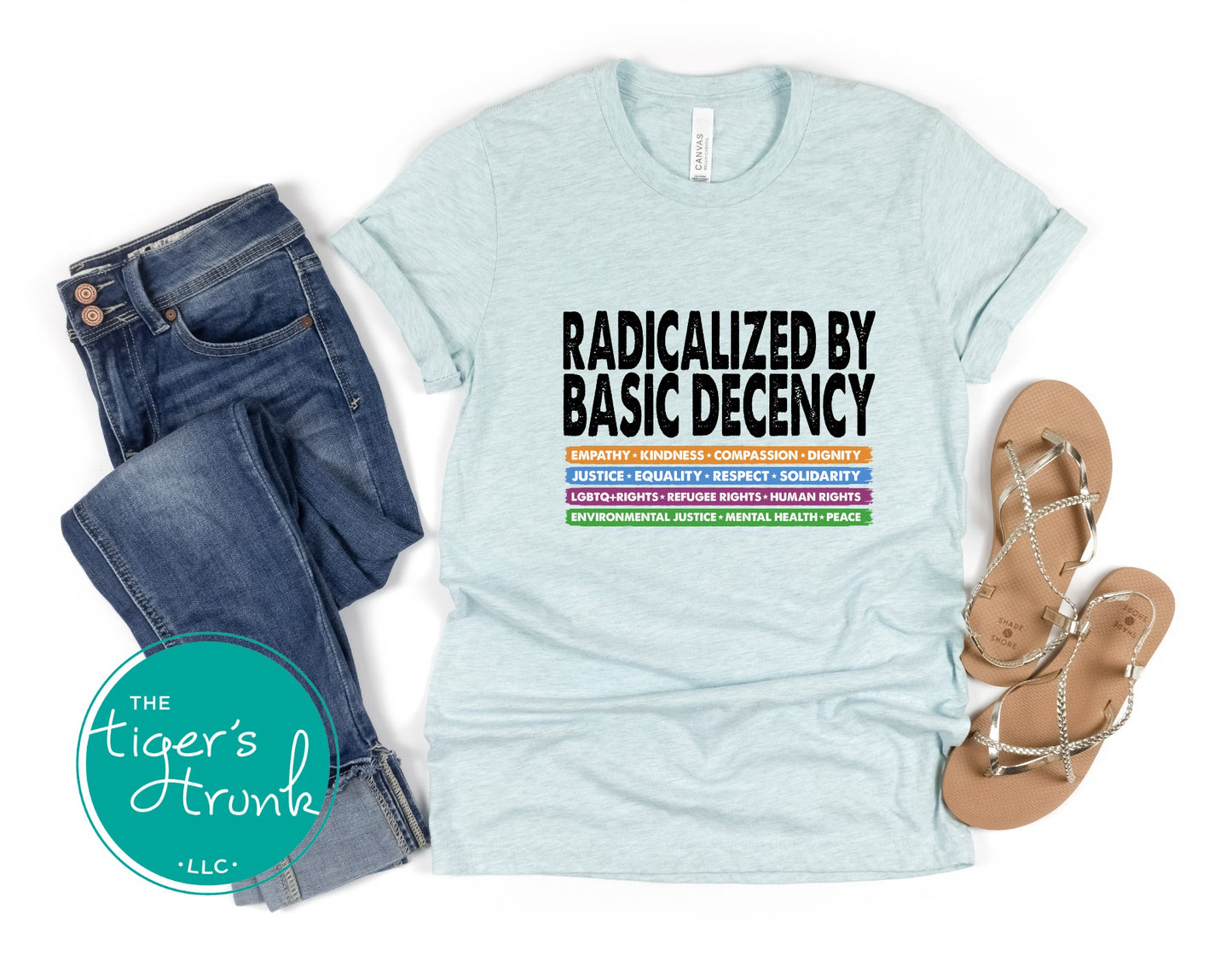 Light blue t-shirt with text, jeans, and sandals on a white background with 'The Tiger's Trunk' logo.