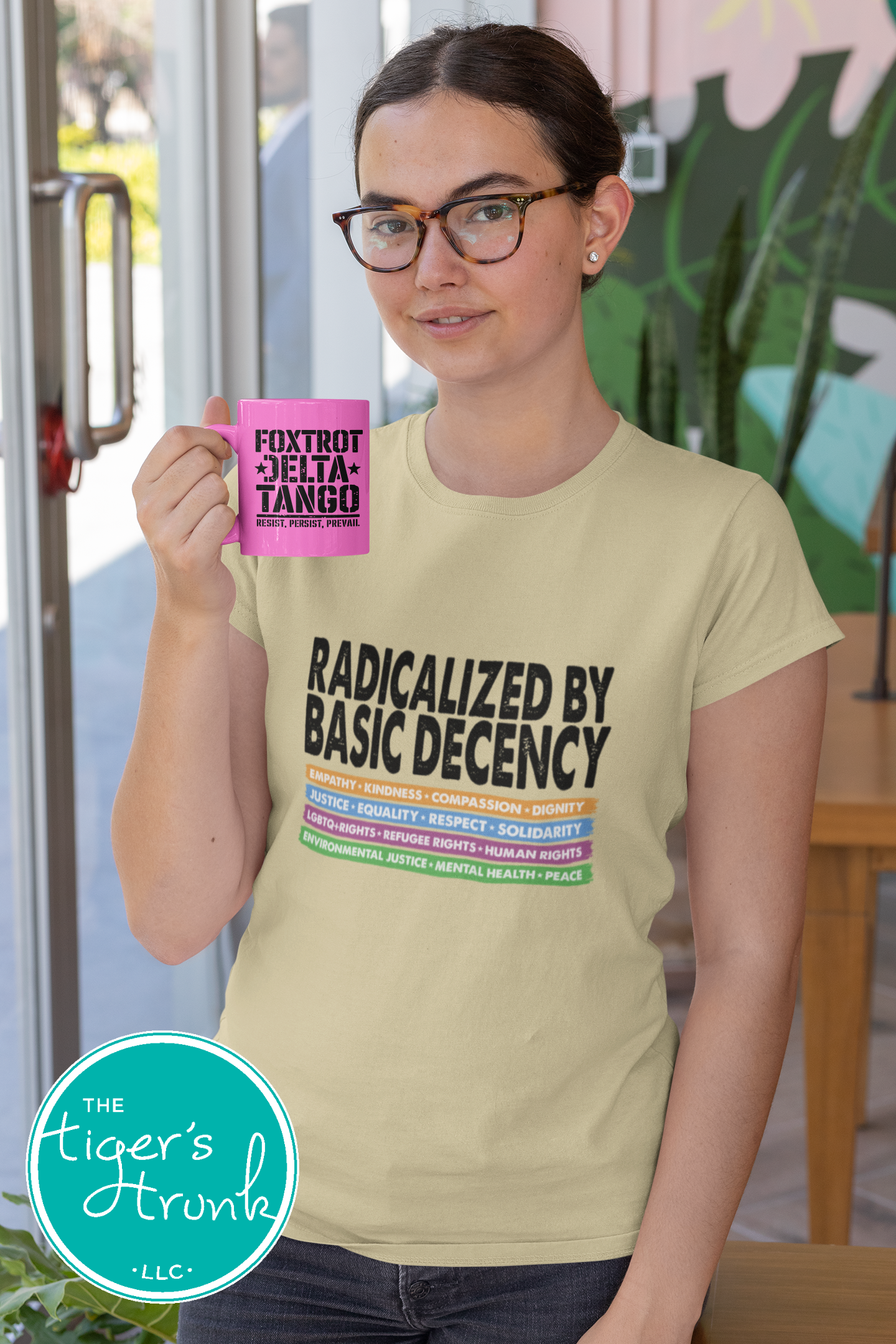 Person wearing a t-shirt with text and holding a mug, standing in an indoor setting.