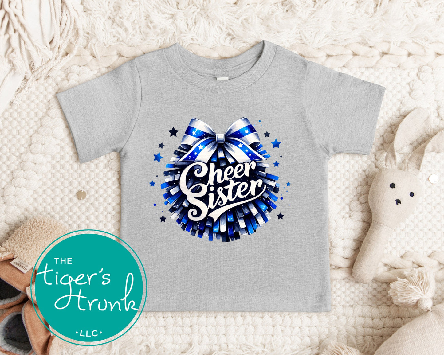 Gray t-shirt with 'Cheer Sister' design on a textured surface, featuring The Tiger's Trunk logo.