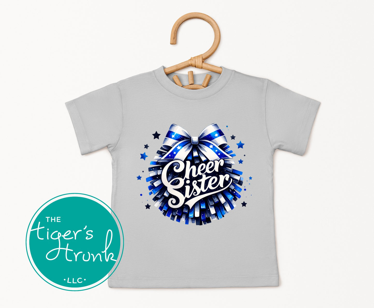 Gray t-shirt with 'Cheer Sister' design on a hanger, featuring The Tiger's Trunk LLC logo.