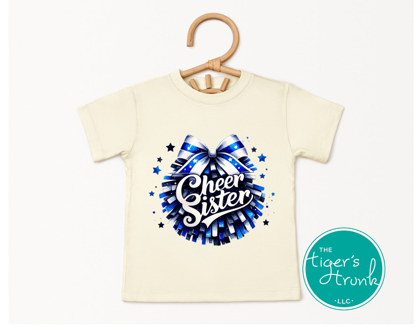 Children's t-shirt with 'Cheer Sister' design on a hanger, brand 'The Tiger's Hyunka' visible.