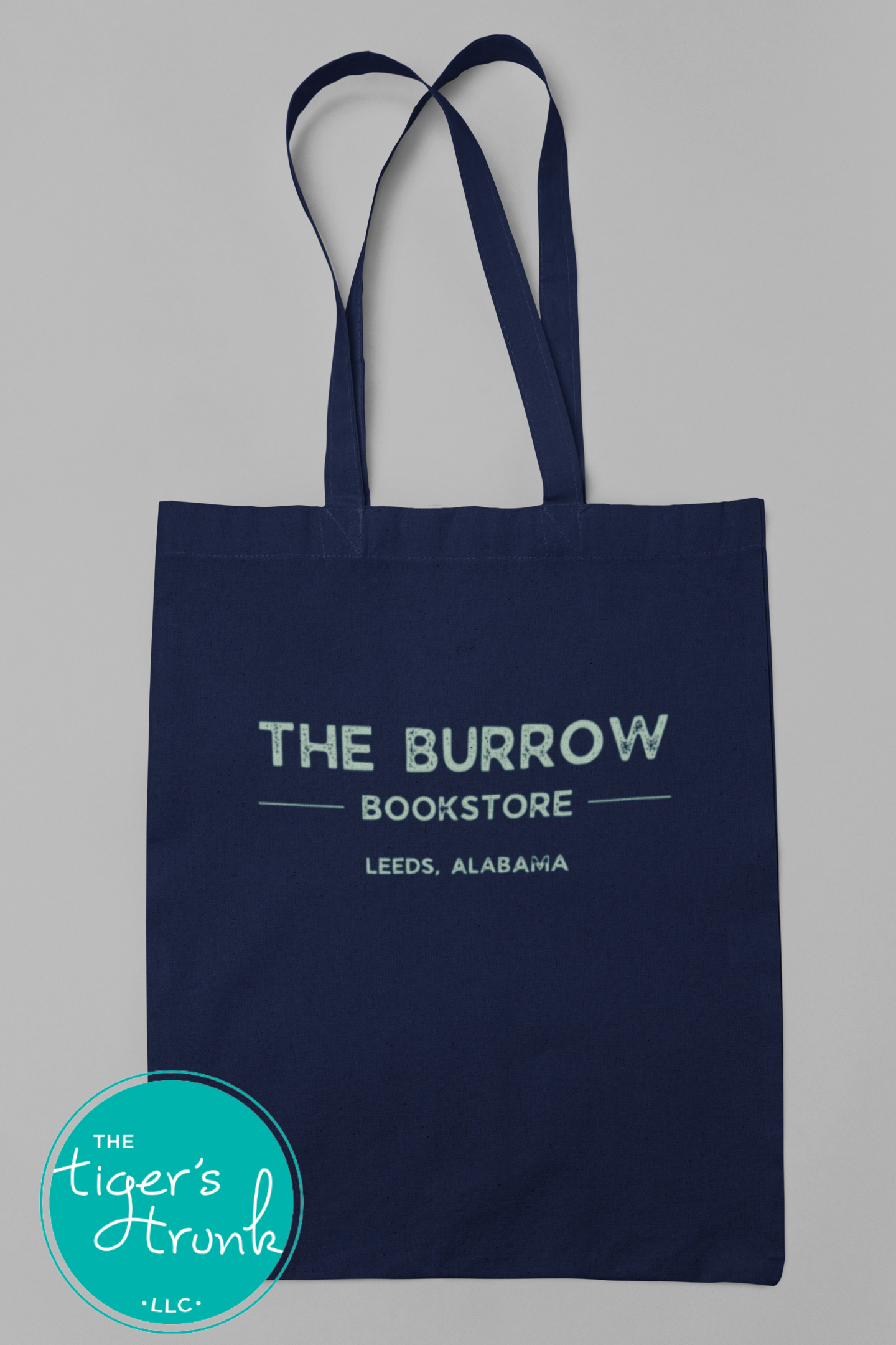 A navy blue canvas shopping bag with 'the burrow bookstore' printed in white text, with a graphic of a tiger's face and the text 'LEEDS, ALABAMA' underneath.