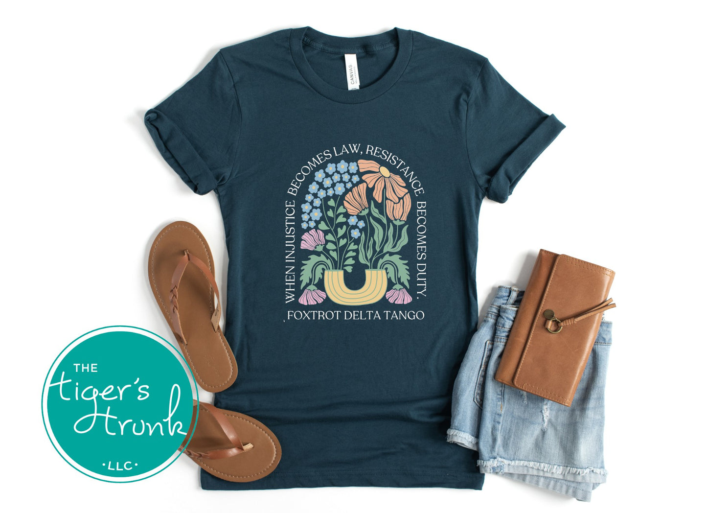 Navy blue t-shirt with floral design and text, paired with sandals and a notebook on a white background.