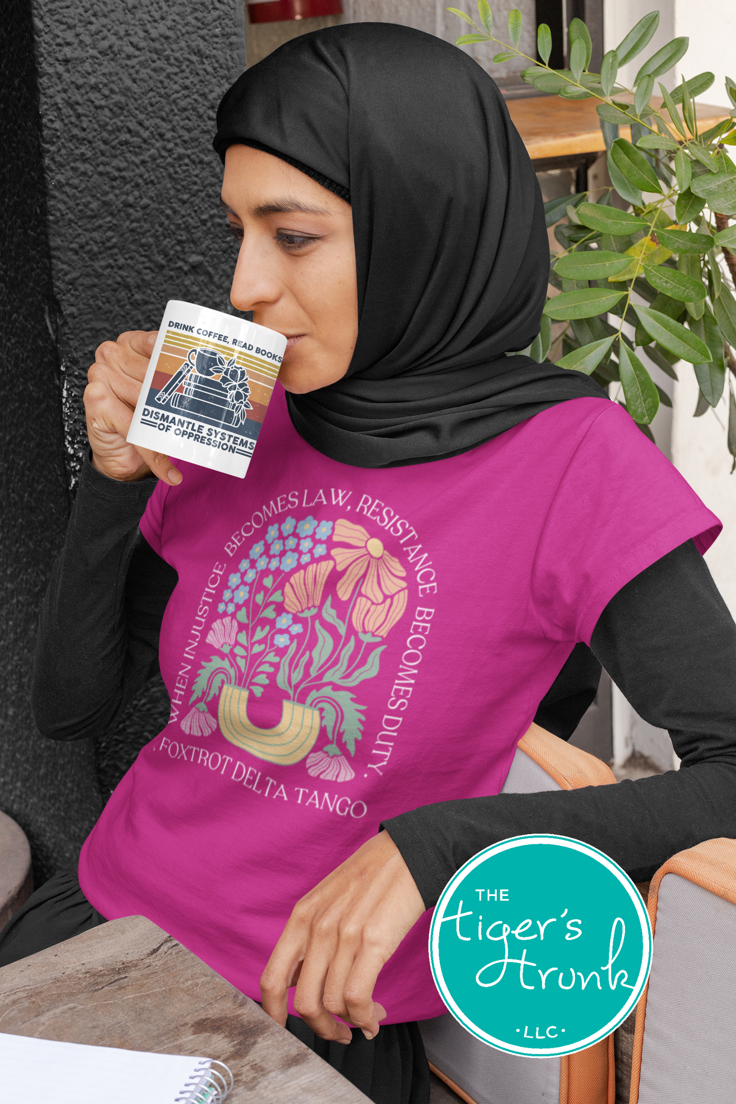 Woman wearing a pink sleeveless shirt with a graphic design, holding a card, sitting in a casual setting.