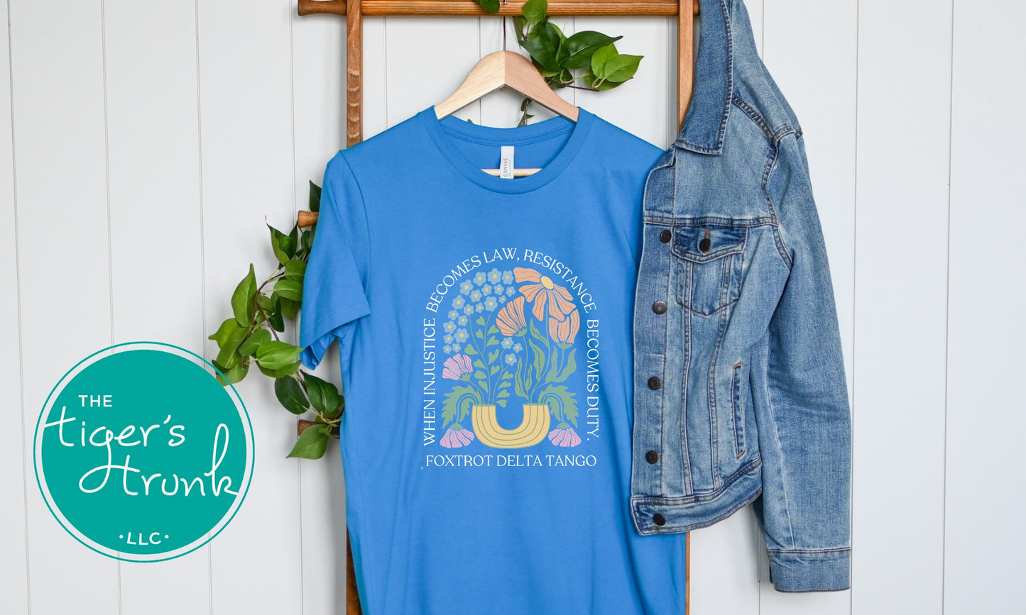 Blue t-shirt with a design and denim jacket on a white wooden background, featuring 'The Tiger's Horn' logo.