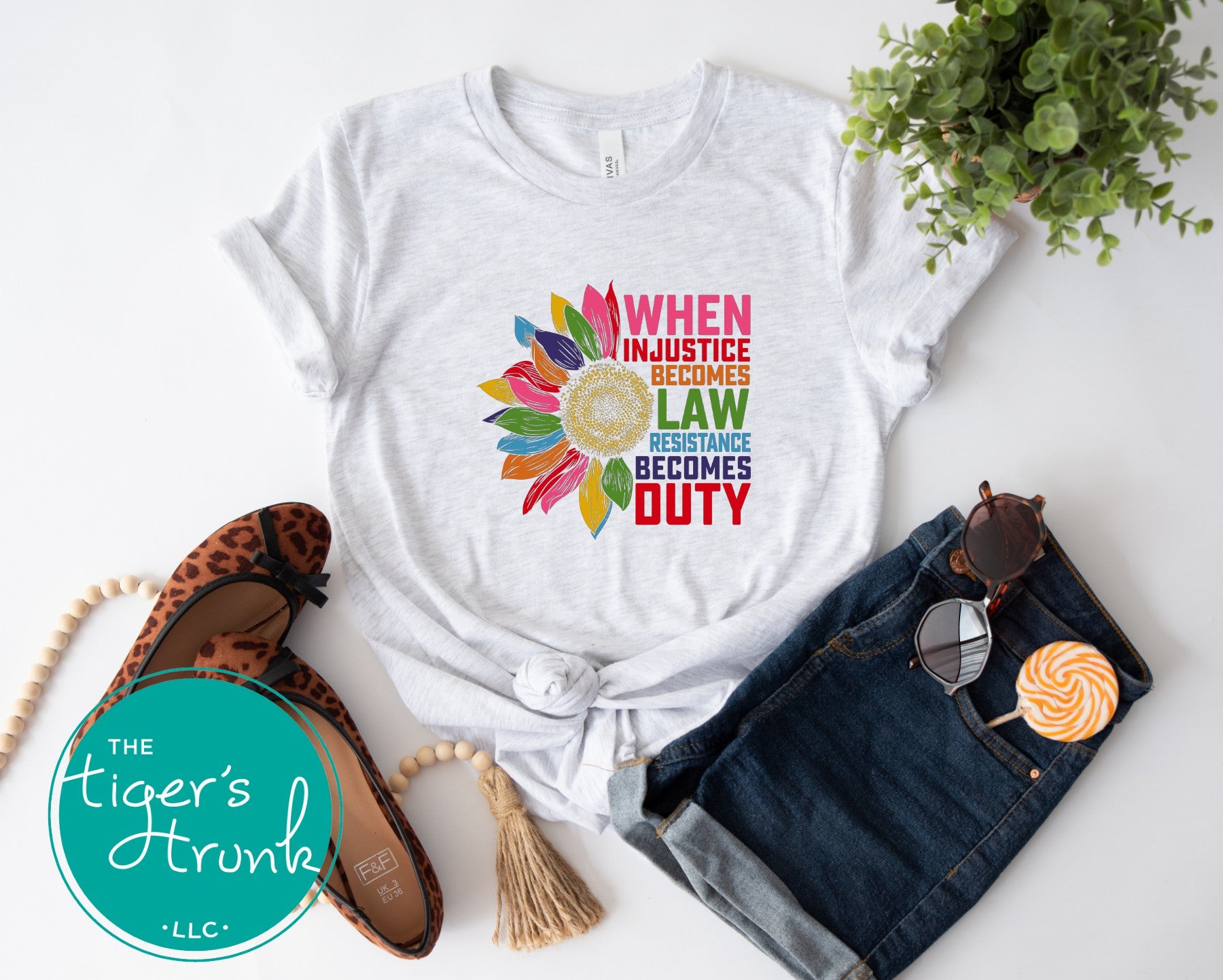 White t-shirt with colorful graphic and text, paired with denim shorts and flats on a white background.