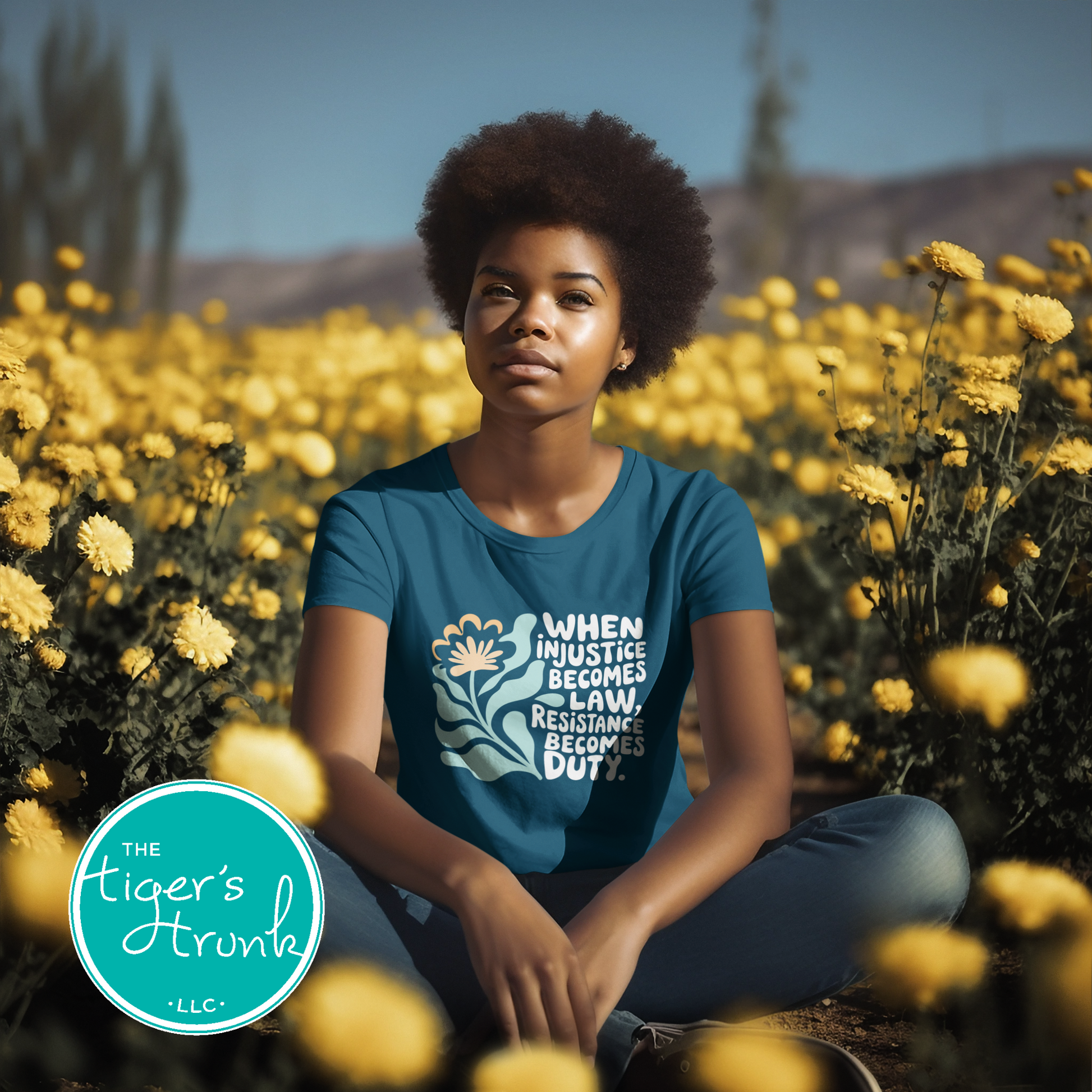 Person wearing a blue t-shirt with text and graphics in a field of yellow flowers, with 'The Tiger's Trunk' logo.