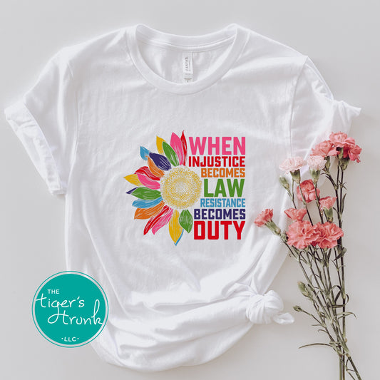 White t-shirt with colorful graphic and text on a light gray background, featuring 'The Tiger's Trunk' logo.