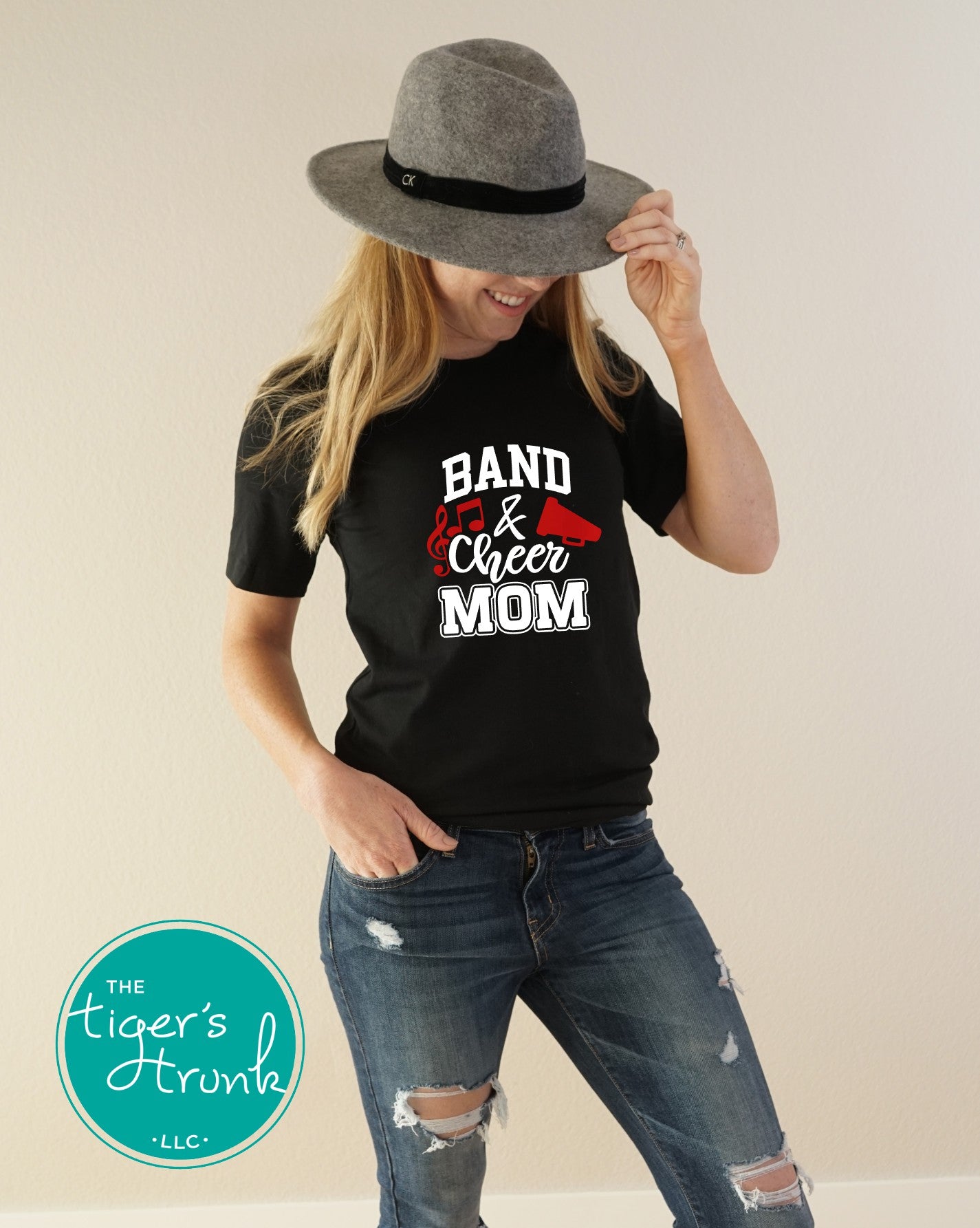 Model wearing black Band and Cheer Mom shirt with white font, red megaphone, and musical notes, customizable school spirit tee in team colors