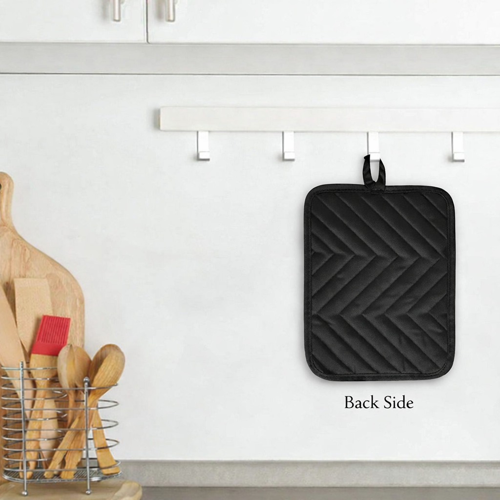 Black quilted pot holder hanging on a kitchen wall with wooden utensils below.