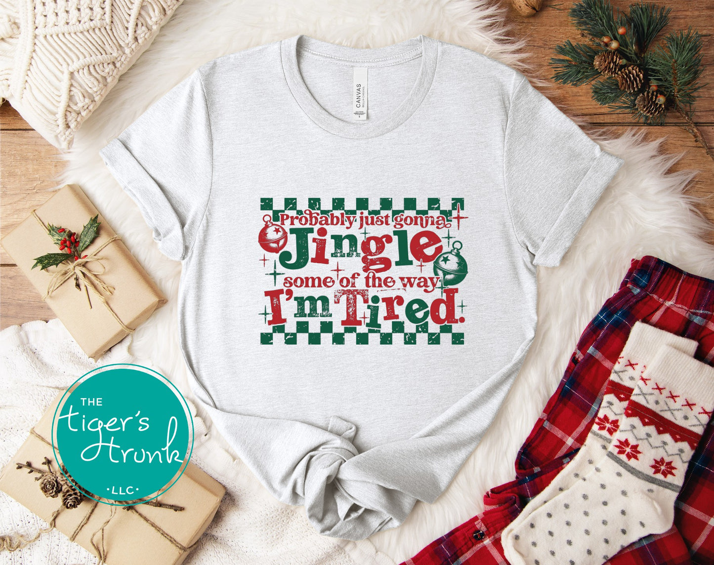 White t-shirt with Christmas-themed text on a festive background with presents and decorations.