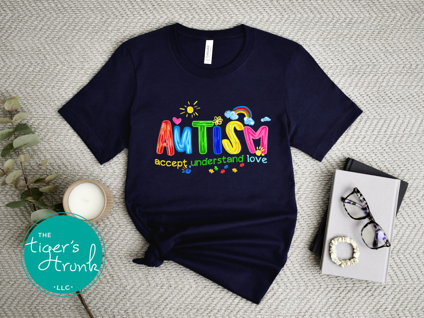 Navy blue t-shirt with colorful 'Autism accept, understand, love' text on a textured surface.