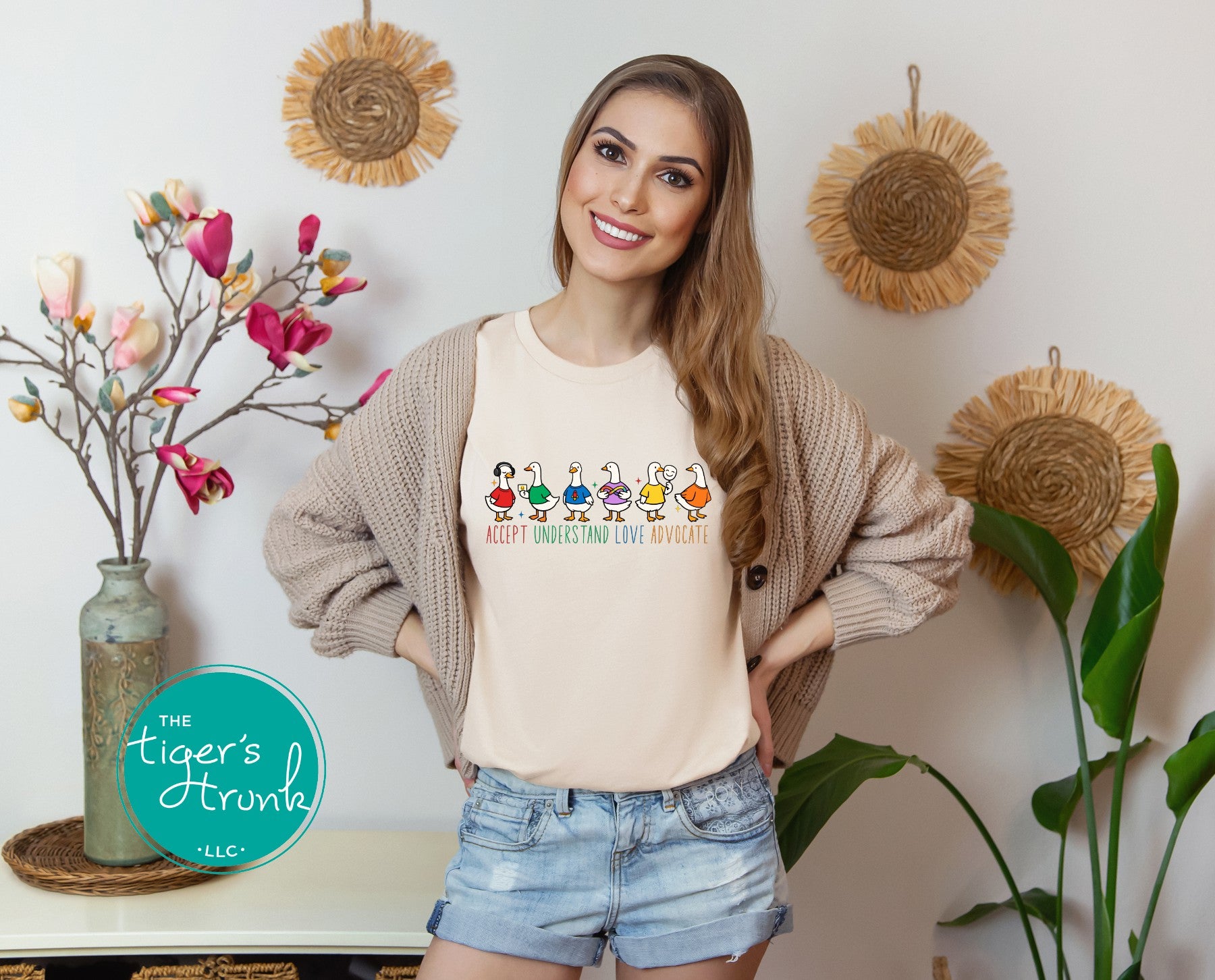woman wearing natural beige autism awareness shirt with colorful ducks and accept understand love advocate message
