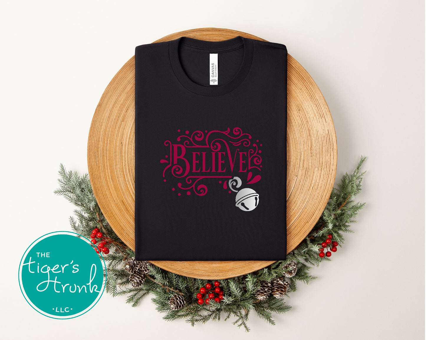 Black t-shirt with 'BELIEVE' design on a wooden board with Christmas decorations