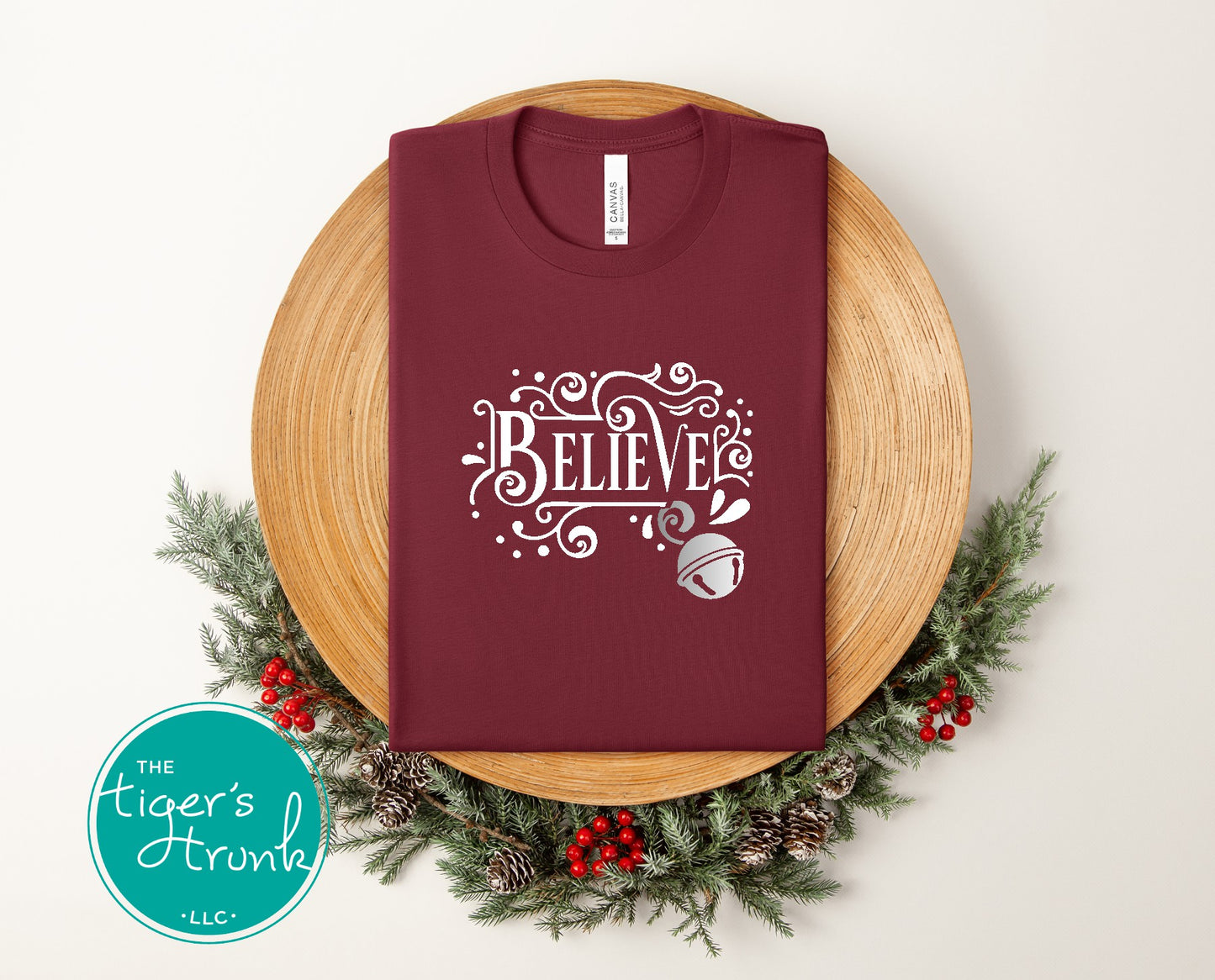 Maroon t-shirt with 'BELIEVE' design on a wooden board with Christmas decorations