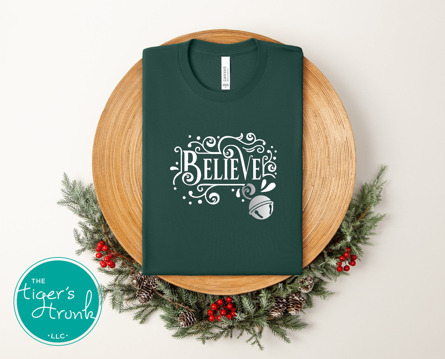 Green t-shirt with 'BELIEVE' design on a wooden board with Christmas decorations