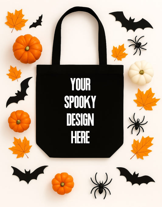 Black tote bag with 'Your Spooky Design Here' text, surrounded by Halloween-themed items like pumpkins, leaves, and bats on a white background.